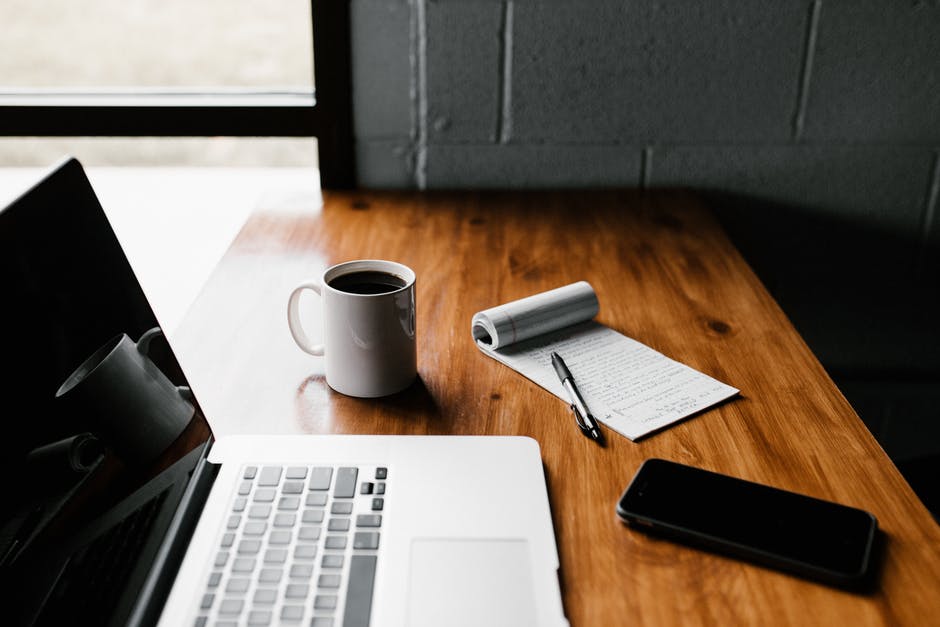 Desk with computer, phone, notebook, coffee